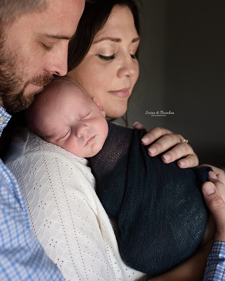 Parents snuggling with their newborn boy during a lifestyle newborn session with Richardson newborn photographer Susan Baraban Photography.
