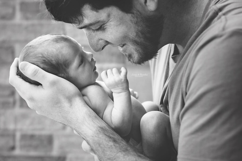 First time dad gazing into his newborn daughter's eyes while they are nose to nose.