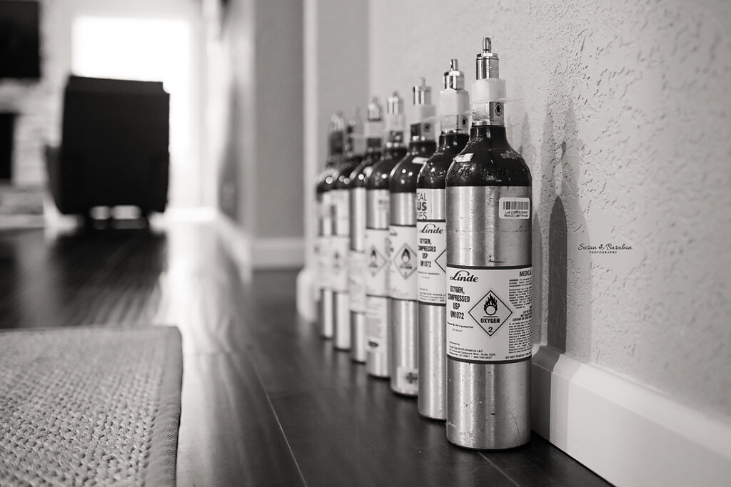 Oxygen tanks lined up against a wall at a lifestyle newborn photo shoot of a premature newborn.