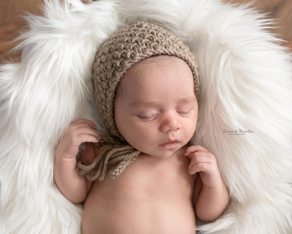 Newborn boy wearing a tan colored knit bonnet during his newborn shoot in Wylie, TX.