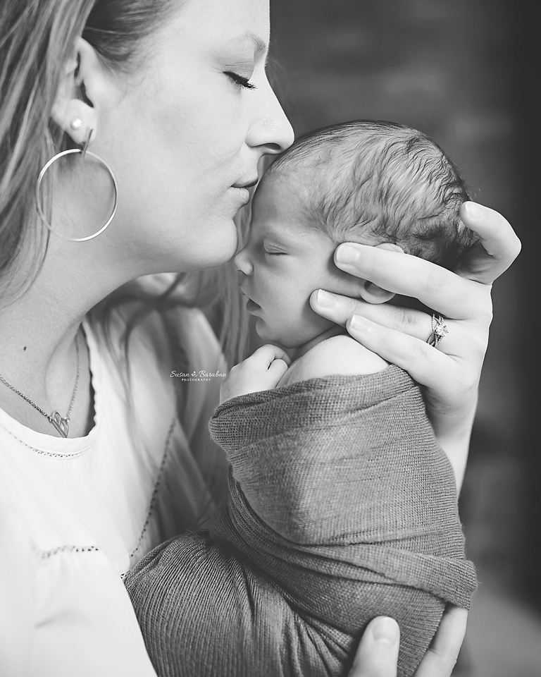 Black and white image of mother kissing her newborn daughter's forehead taken by Allen Newborn Photographer Susan Baraban Photography.
