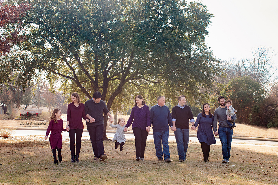 An extended family holding hands and walking at their lifestyle family photo shoot at Prairie Creek Park in Richardson.