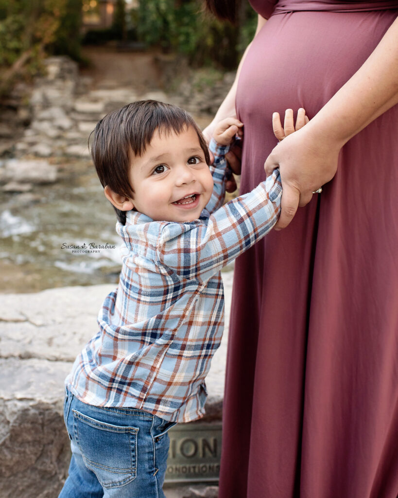 Big brother touching his mother's pregnant belly at a lifestyle maternity session with Susan Baraban Photography.