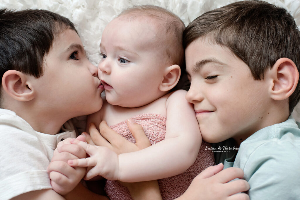 Brothers cuddling their new baby sister at her newborn photo shoot in Richardson, TX.

