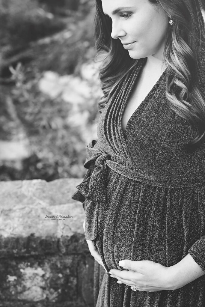 Black and white image of an expectant mother cradling her belly at a maternity session in Turtle Creek Park.