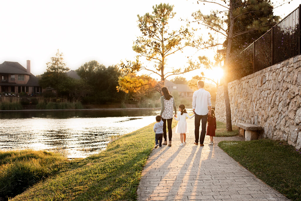 Family of 5 walking along the water's edge as the sun sets in front of them at Adriatica Village during their lifestyle family photo shoot.